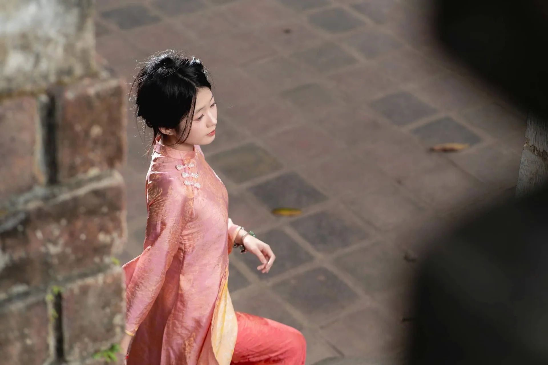 Graceful Asian Young Woman in Traditional Pink Attire: Timeless Beauty by an Ancient Wall