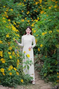 Radiant Youth: Vietnamese Girl in Elegant White Ao Dai Amidst Golden Blooms - image 1