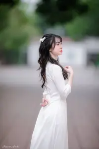 Graceful Vietnamese Girl in Elegant White Ao Dai with Sweet Finger Heart Gesture - image 5