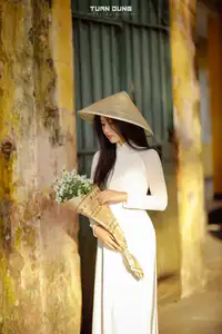 Captivating Beauty: Vietnamese Girl in White Ao Dai with Delicate Daisies. - image 0
