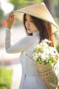 Captivating Beauty: Vietnamese Girl in White Ao Dai with Delicate Daisies. - image 2