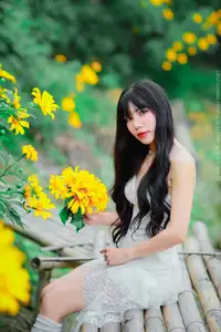 Graceful Young Woman in White Dress Amidst Vibrant Yellow Flowers 1000026997 - image 1