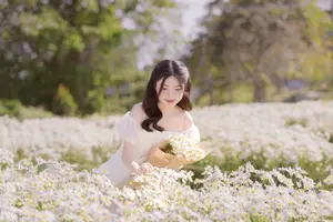 Serene Beauty: Young Woman in White Flower Field, Embracing Tranquility Under Gentle Sunlight - image 1