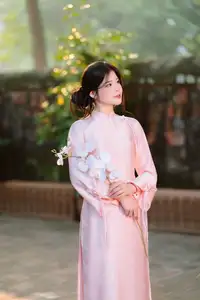 Elegant Vietnamese Beauty: Young Woman Gracefully Posing in Pink Ao Dai with White Orchids 1000026874 - image 1