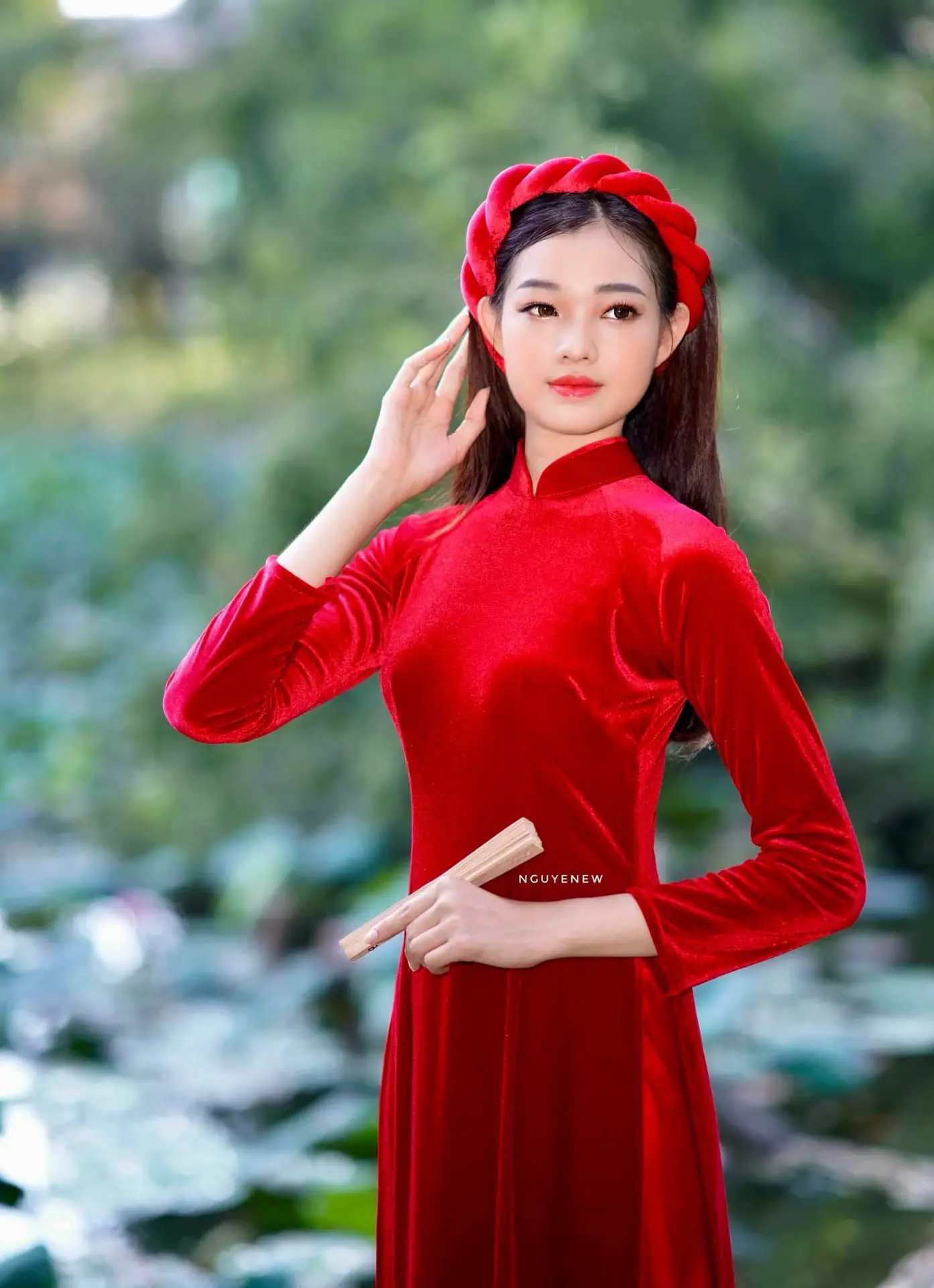 Discover the enchanting beauty of a Vietnamese woman in a traditional Red Ao Dai by the tranquil water.
